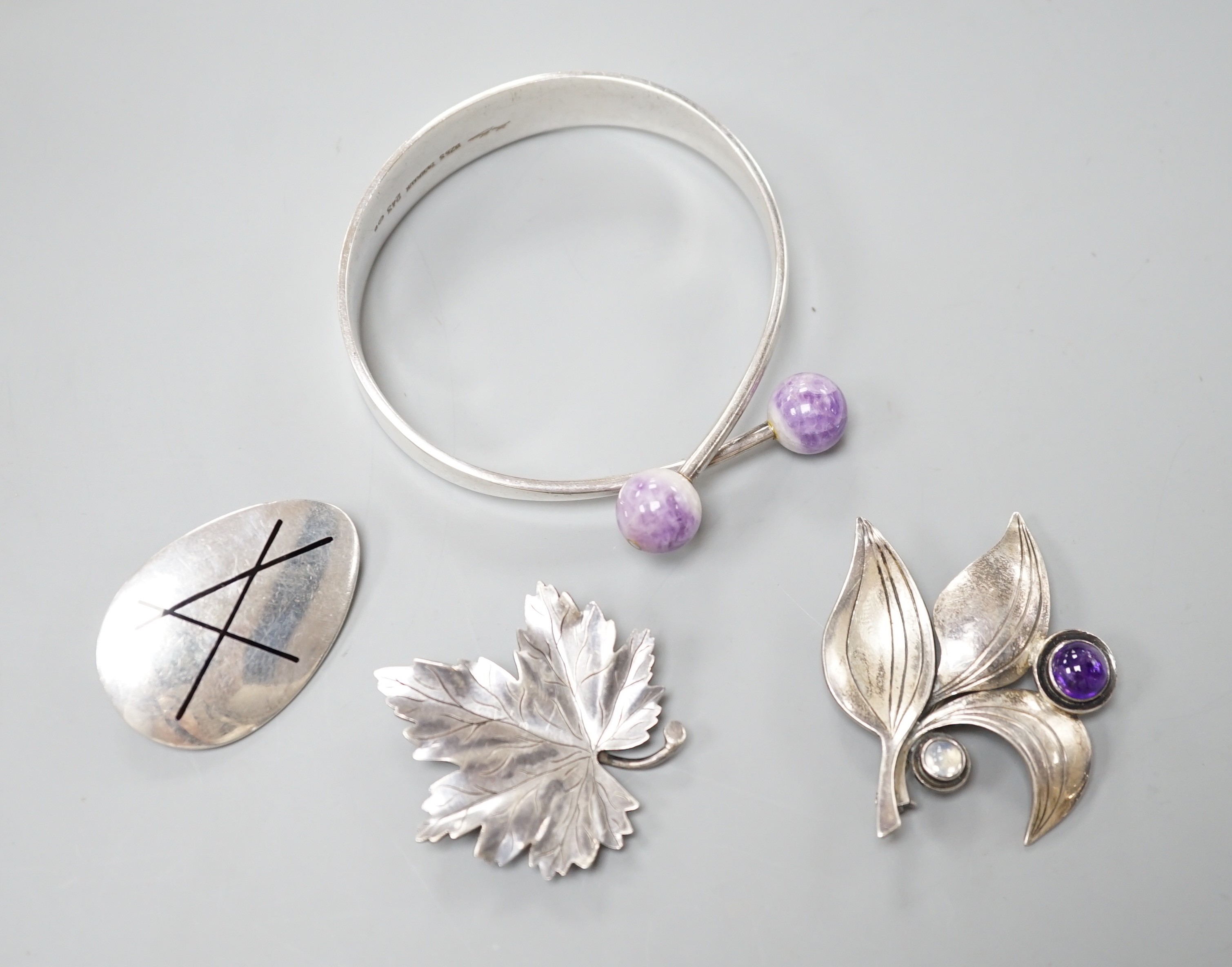 Four items of 20th century Scandinavian white metal jewellery, including a brooch and amethyst quartz set bangle by Hans Hansen and two Swedish white metal leaf brooches, bangle interior diameter 62mm.